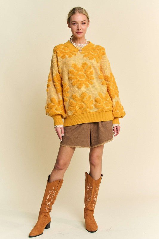 Woman wearing a gold flower texture round neck sweater with dropped shoulders, paired with brown boots and a skirt.