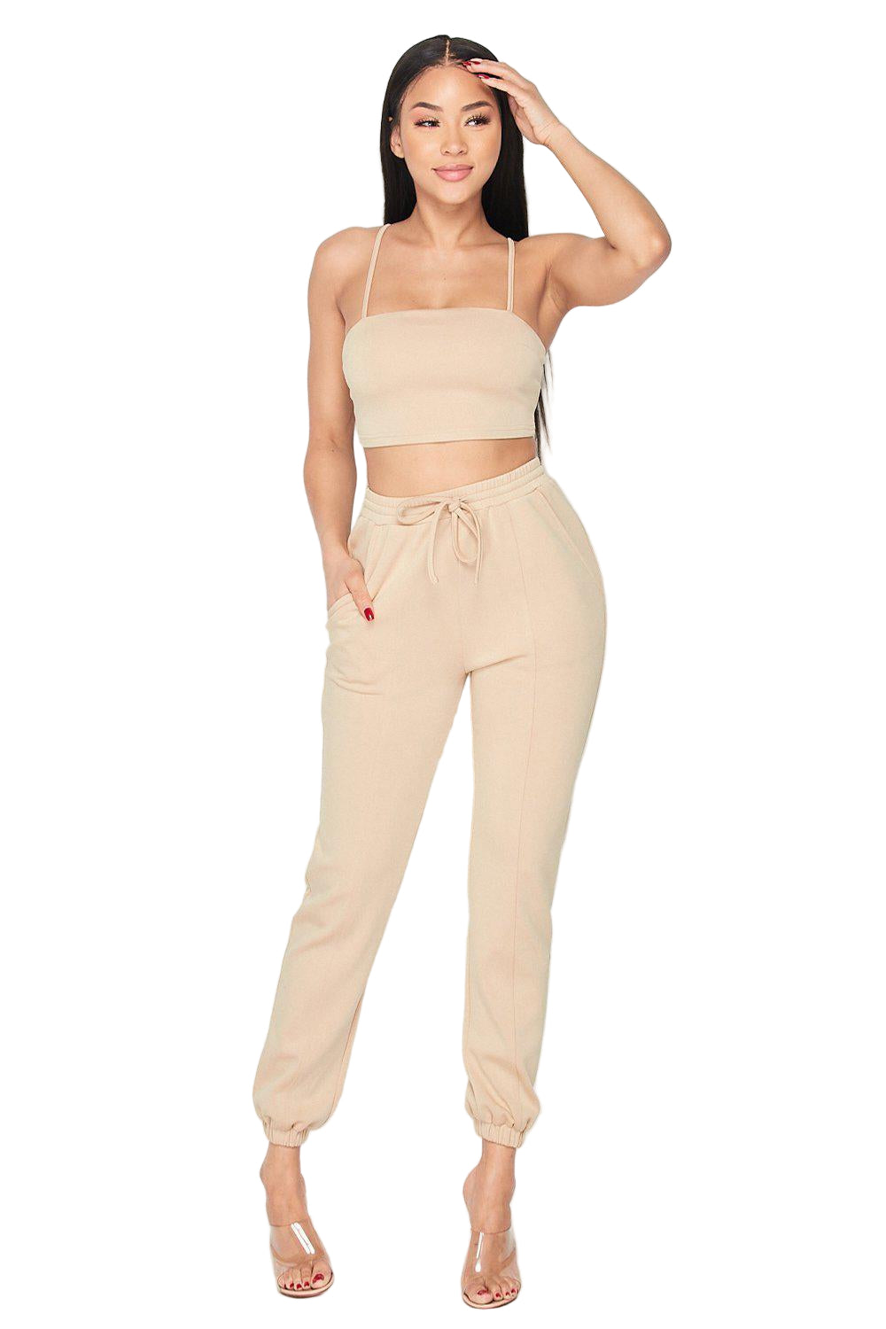 Beige two-piece set featuring a crop top and jogger pants, made of rayon, polyester, and spandex. Fashionable and comfortable outfit.