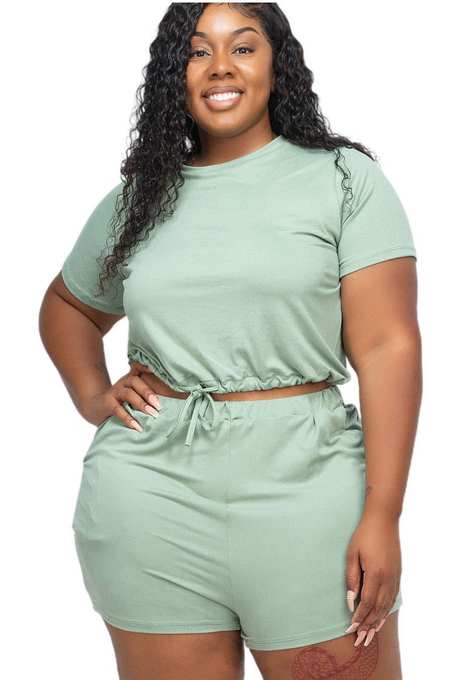 Plus size woman wearing a soft green short sleeve crop top and shorts set, showcasing comfortable and stretchy casual wear.