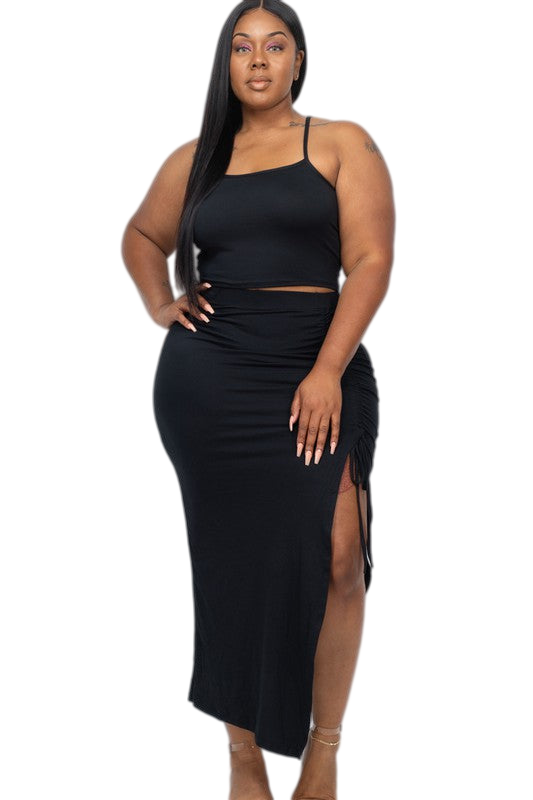 Plus size black two-piece skirt set with spaghetti strap top and ruched side detail skirt, featuring a side slit.