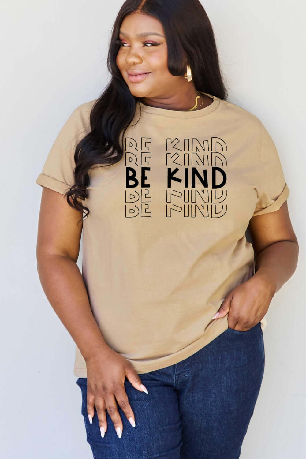 Plus size woman wearing a beige "Be Kind" graphic tee from Curvy Graphic Tees collection.