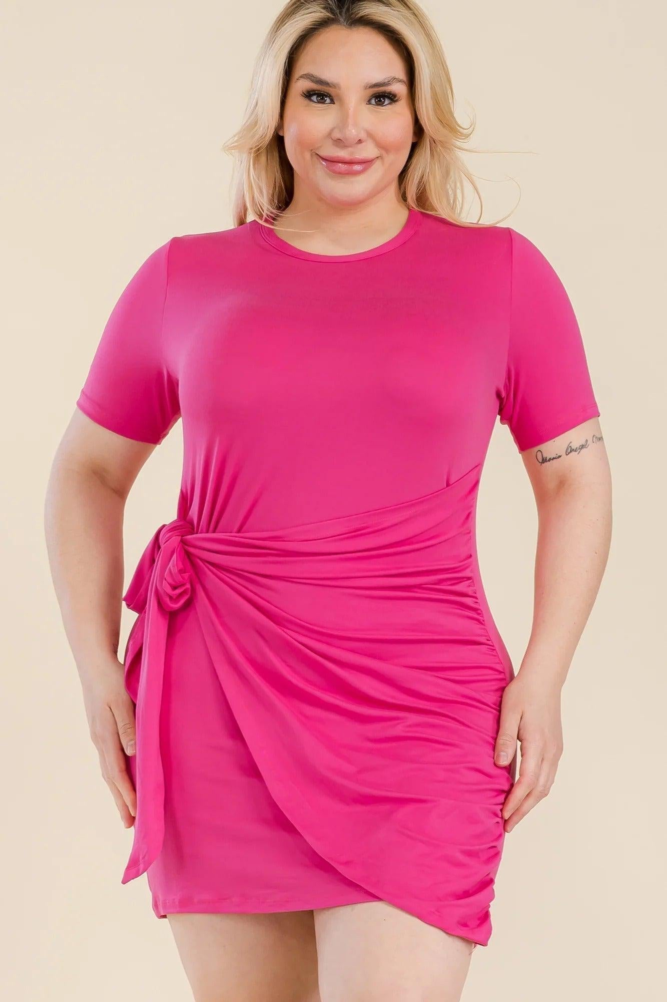 Plus size woman wearing a vibrant pink short sleeve dress with a stylish side tie, celebrating curves and confidence.