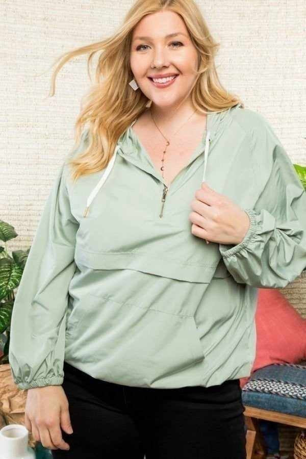 Woman modeling a light green plus-size hoodie, showcasing comfortable and stylish curvy fashion for modern women.