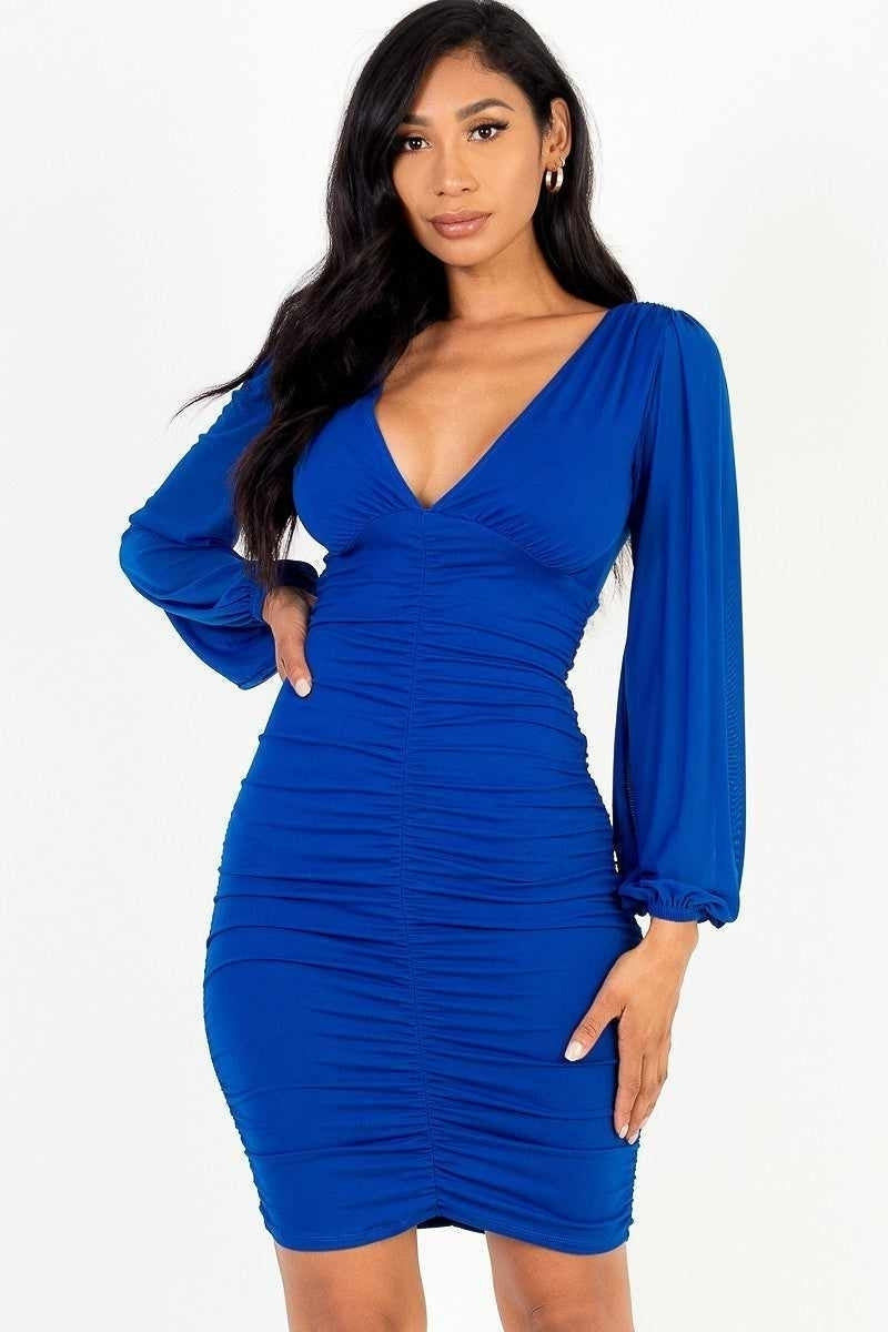 Stylish woman in a blue V-neck long sleeve mini dress, perfect for a chic and flirty look.