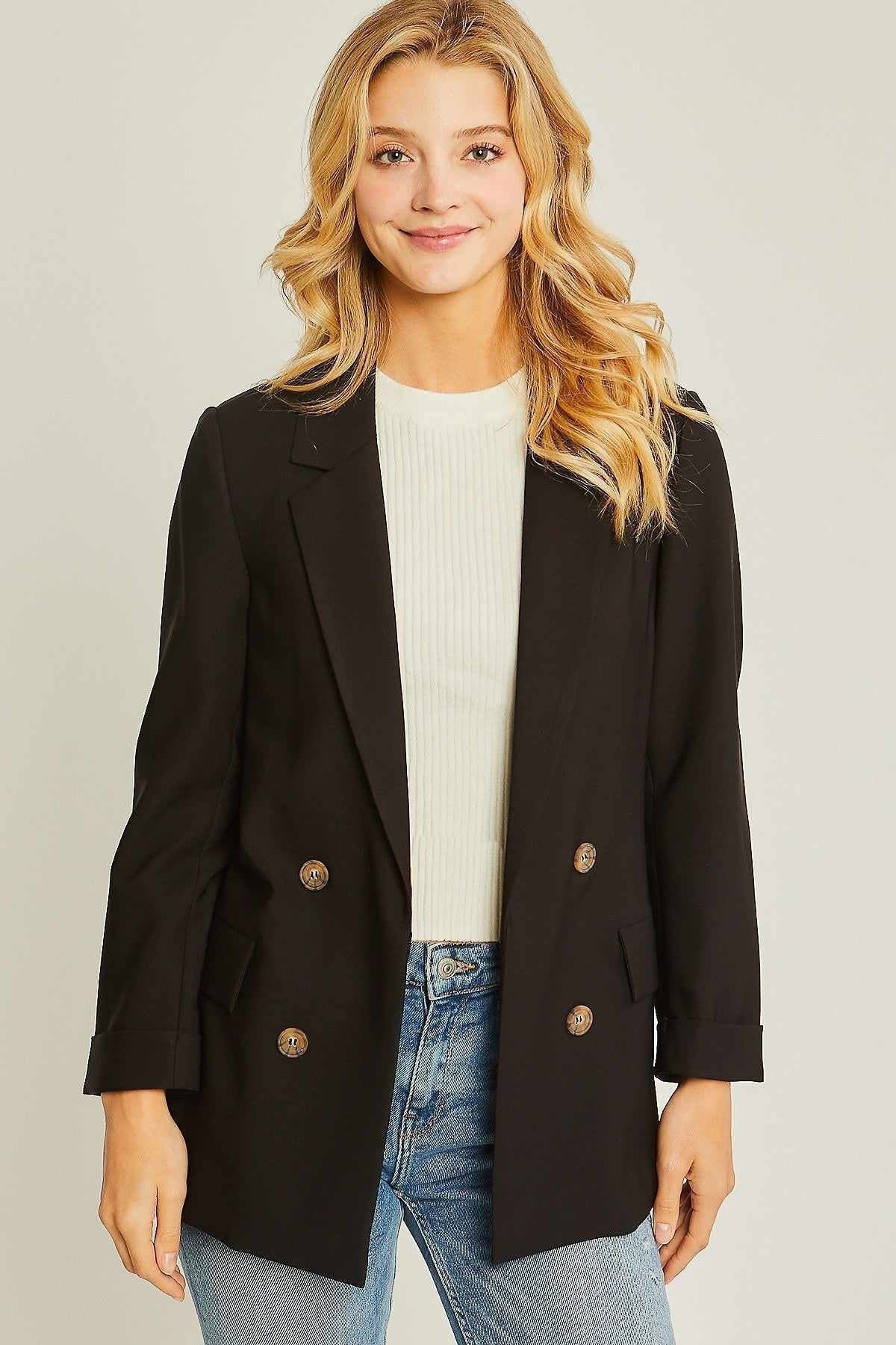 Woman wearing a stylish black blazer and jeans, showcasing fashion-forward outerwear for women.