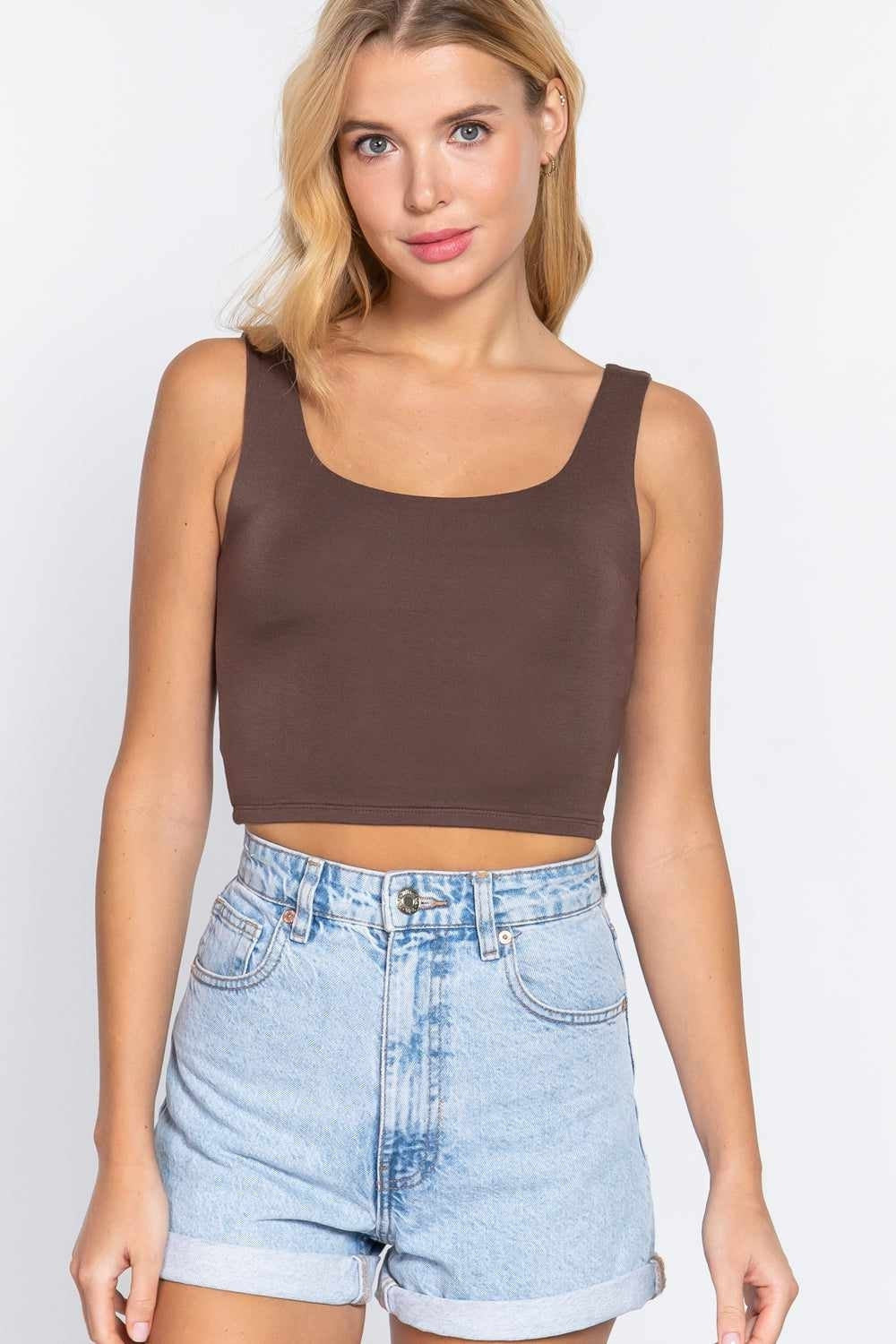 Woman in trendy brown tank top and denim shorts showcases chic fashion style.