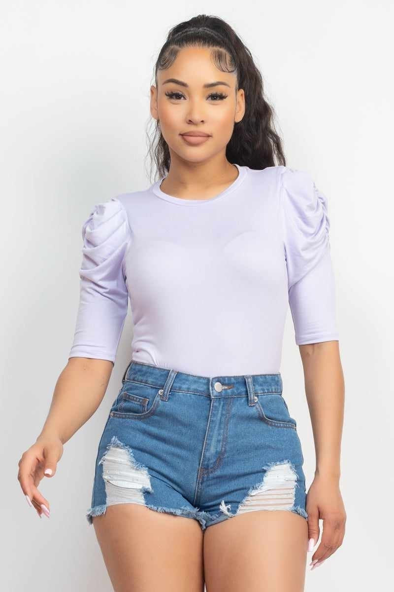 Woman wearing trendy lilac top with puff sleeves and denim shorts, showcasing stylish casual fashion for women.