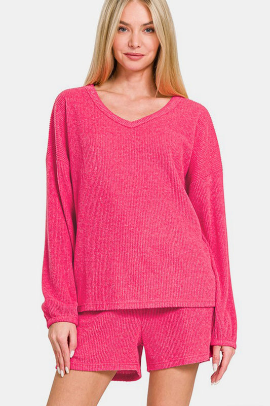 Woman wearing Zenana V-Neck Long Sleeve Ribbed Top and Shorts Set in pink, showcasing casual chic style.