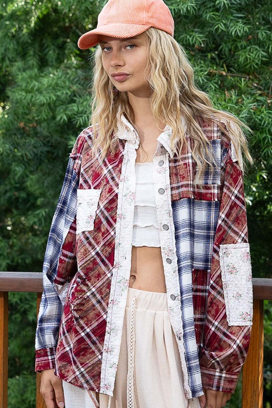 Woman wearing a burgundy patchwork plaid button-up shirt with raw hem and exposed seams, standing outdoors in casual attire.