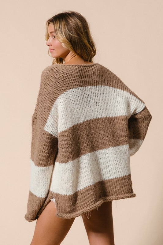 Woman wearing BiBi Slit Striped V-Neck Dropped Shoulder Sweater, showcasing brown and white striped knit design with casual fit.