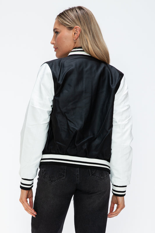 Woman wearing black and white PU leather bomber jacket with contrast snap down design.