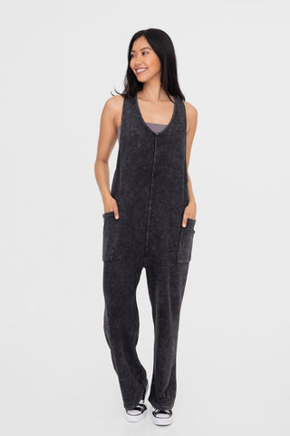 Woman wearing black mineral-washed V neck overalls with pockets, 100% cotton, showcasing basic style and comfort.