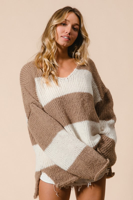 Woman wearing BiBi Slit Striped V-Neck Dropped Shoulder Sweater in brown and white, showcasing trendy and relaxed style.