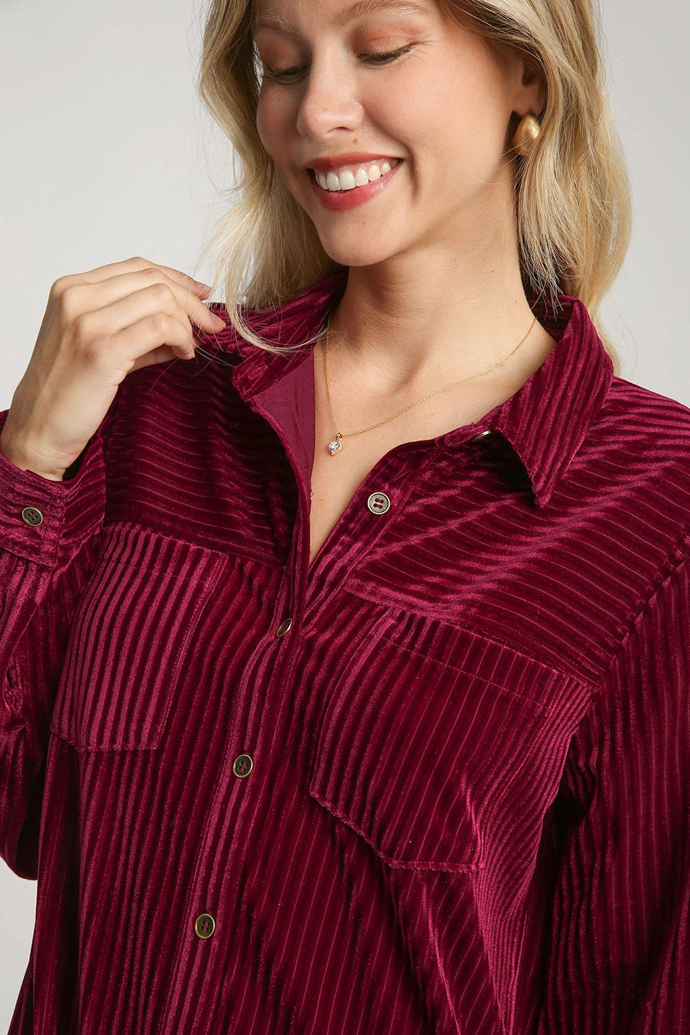 Woman wearing burgundy texture curved hem button-down shirt dress with buttoned pockets and slight stretch.