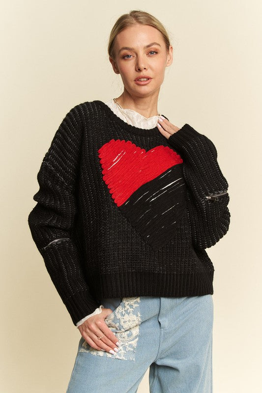 Woman wearing black contrast heart dropped shoulder sweater with ribbed style, paired with blue jeans.