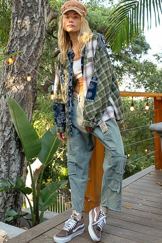 Woman wearing a Moss Patchwork Plaid Button Up Shirt with exposed seams and raw hem, styled with casual pants and sneakers outdoors.