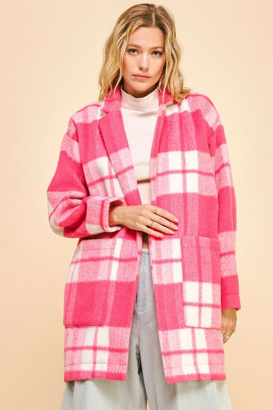 Pink plaid open front longline coat with pockets and drop shoulder design, worn over a white top and light wash jeans.