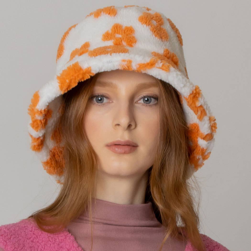 Floral winter sherpa bucket hat with orange flower pattern and adjustable strings, made of 100% polyester, worn by a woman.