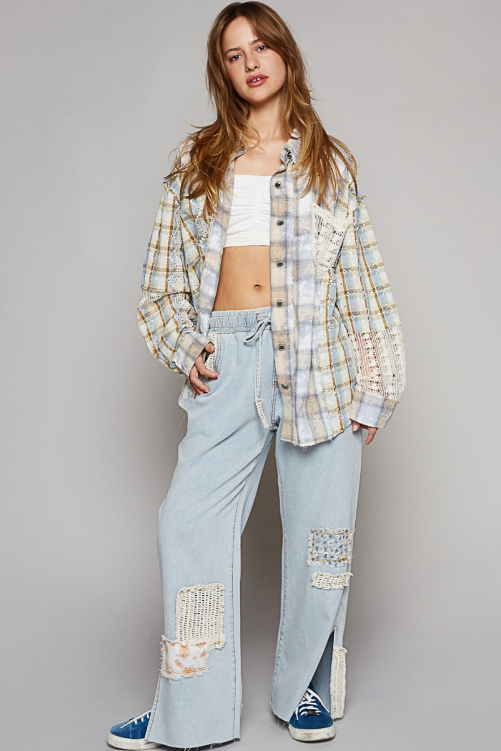 Woman wearing long sleeve embroidered crochet plaid shirt with lace detail, paired with light blue pants and sneakers.