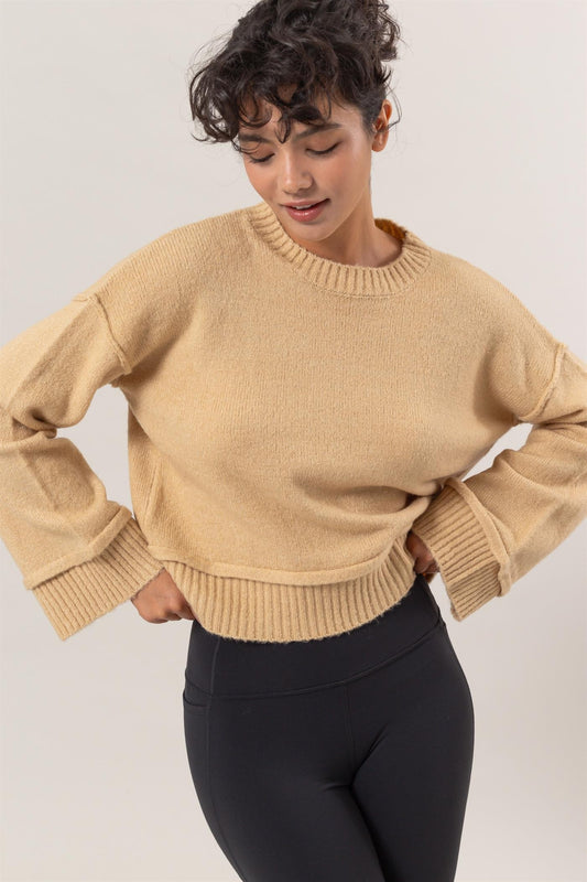 Woman wearing HYFVE round neck dropped shoulder ribbed sweater in beige, showcasing chic and versatile fashion style.