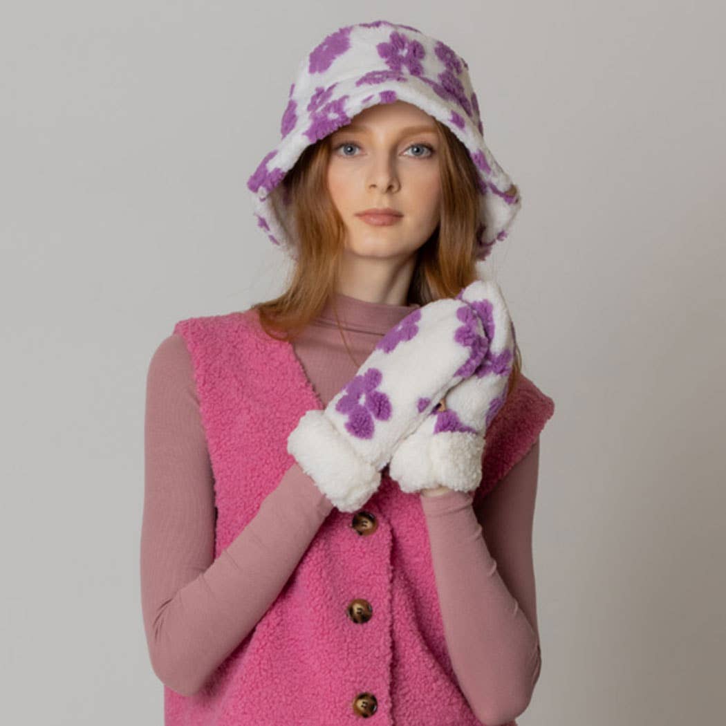 Woman wearing winter flower pattern sherpa bucket hat and matching gloves, styled with a pink sherpa vest over a long-sleeve top.