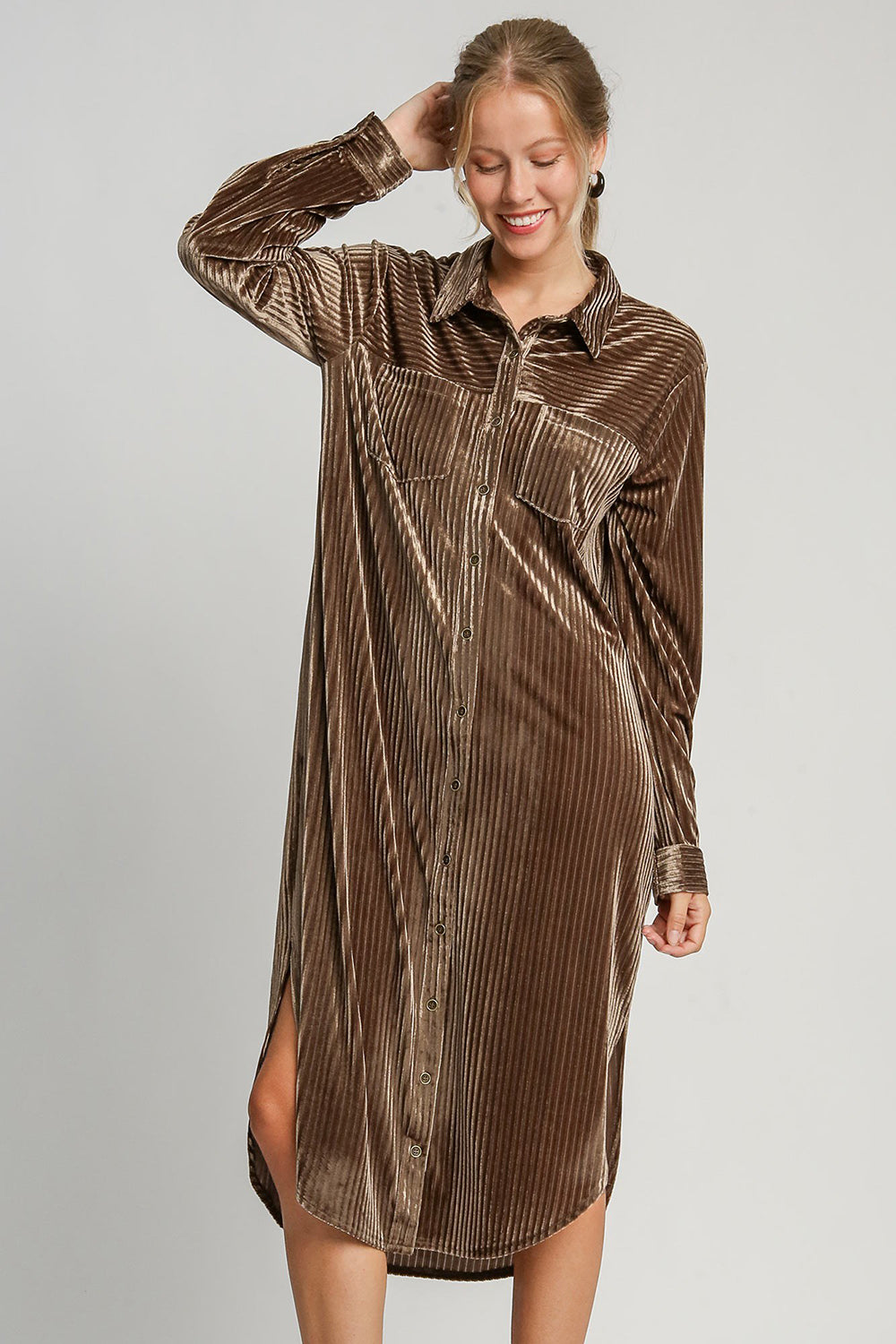 Woman wearing a brown textured curved hem button down shirt dress with side slit and chest pockets, made of slightly stretchy polyester spandex blend.