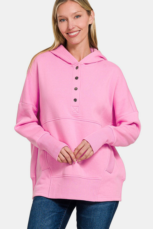 Pink half snap long sleeve hoodie with kangaroo pocket, worn by model, featuring ribbed design and slightly stretchy cotton polyester blend.