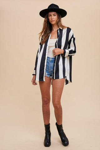 Woman wearing fall striped dropped shoulder button-up shirt with black hat and denim shorts, showcasing casual chic style.