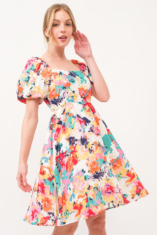 Multicolor square neck puff sleeve floral dress with ruched bodice, featuring colorful blossoms and an elegant, pocketed A-line design.