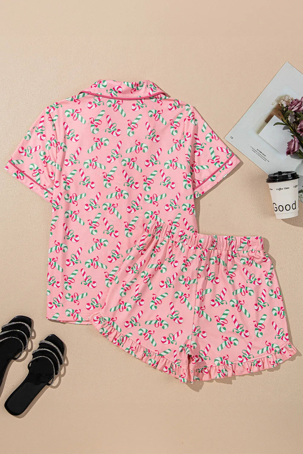 Pink candy cane collared neck top and shorts pajama set with holiday pattern on beige background.