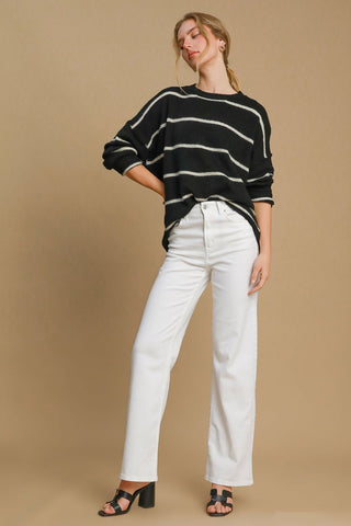 Woman wearing a wool blend striped round neck sweater with white jeans and black heels.