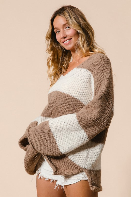 Woman wearing a BiBi Slit Striped V-Neck Dropped Shoulder Sweater with brown and white stripes, perfect for a modern casual look.