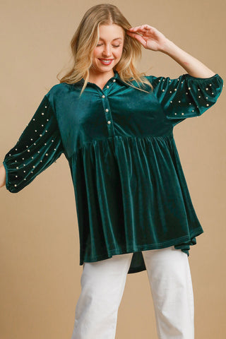 Hunter green velvet babydoll blouse with buttoned half sleeves and tiered design, worn by smiling woman.