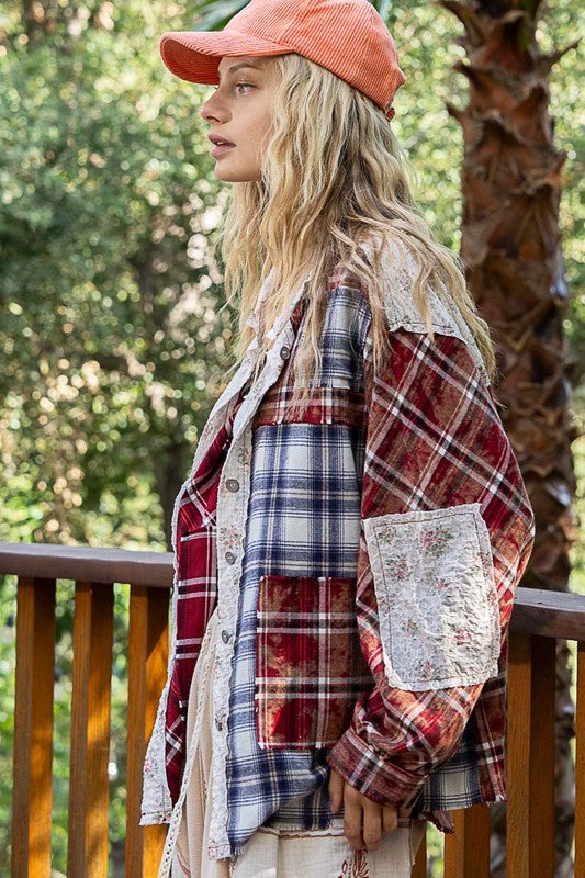 Woman wearing a burgundy patchwork plaid button-up shirt with raw hem and exposed seams, standing outdoors next to a wooden railing.