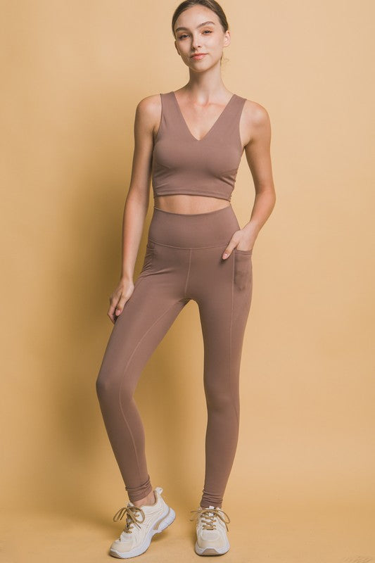 Woman wearing high waist leggings with side pockets, basic style, stretchy opaque fabric, in beige color.