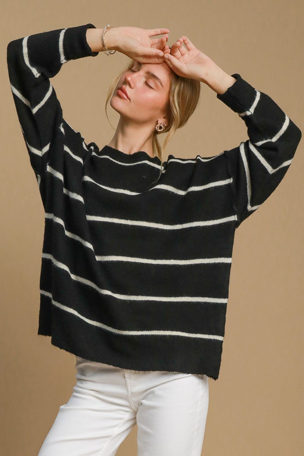 Woman wearing a wool blend striped round neck sweater in black and white.