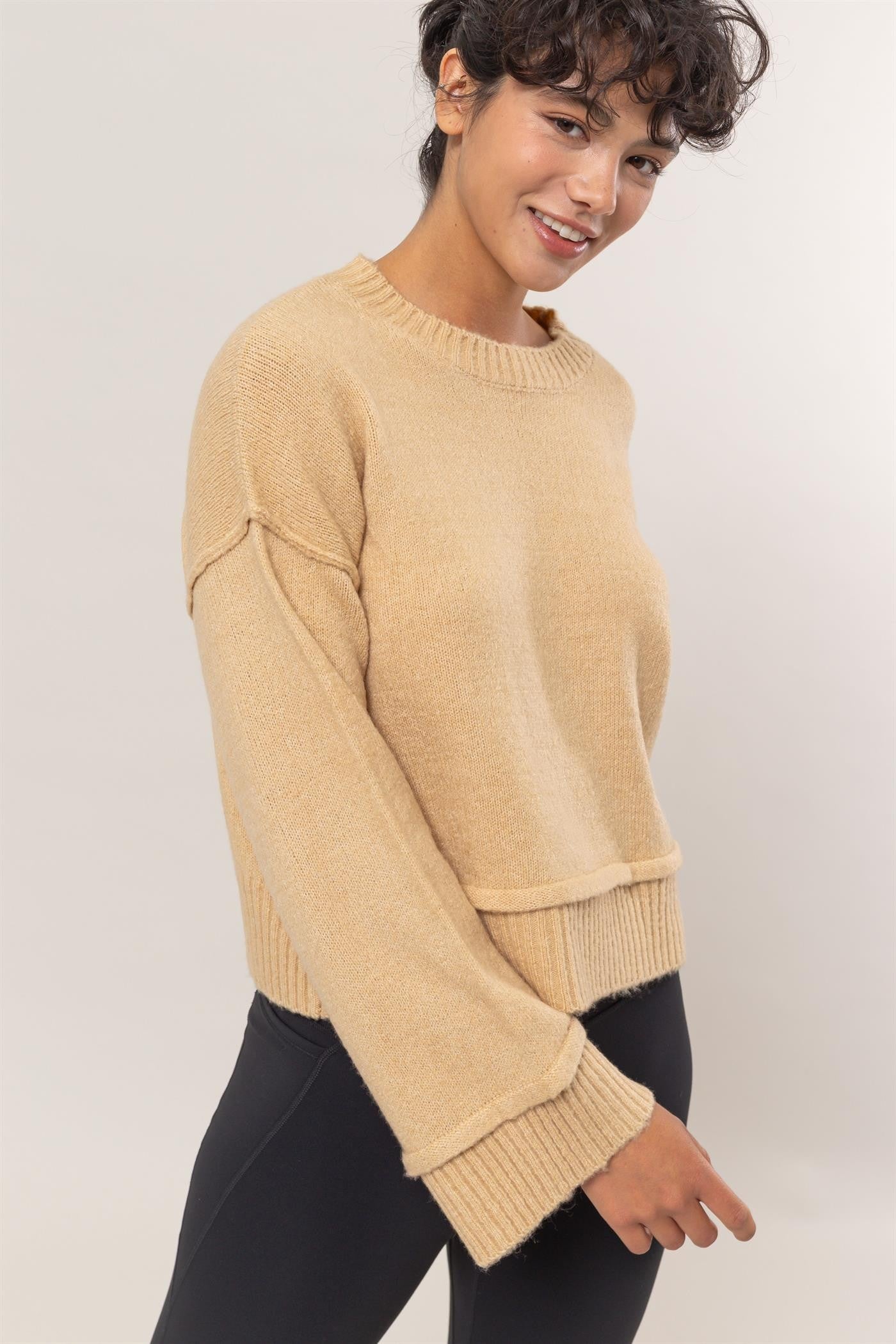 Woman wearing HYFVE Round Neck Dropped Shoulder Ribbed Sweater in beige, showcasing a relaxed and stylish look.