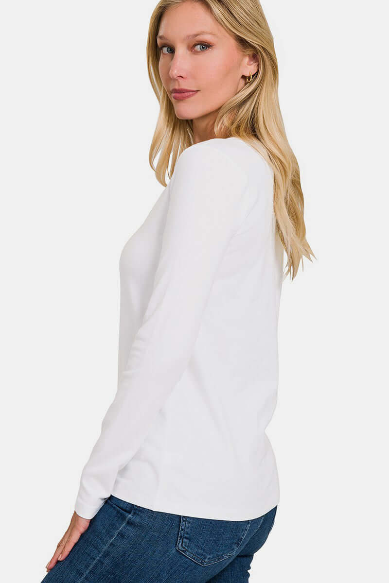 Woman wearing white V-neck long sleeve t-shirt with slight stretch, made from cotton and spandex, paired with jeans.