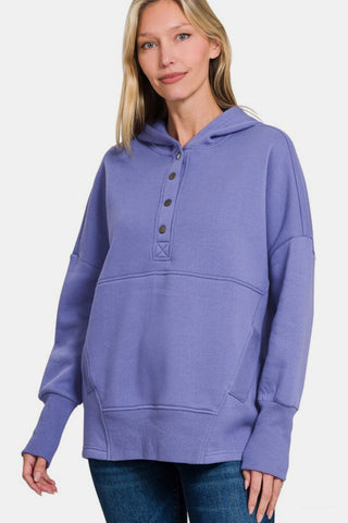 Woman wearing Zenana half snap long sleeve hoodie with kangaroo pocket in purple, showcasing sporty and comfortable fashion.