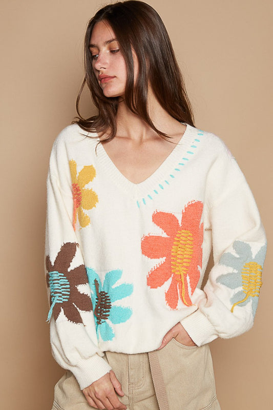 Woman wearing ivory V-neck long sleeve sweater with colorful flower fringe design, made from acrylic, nylon, and polyester.