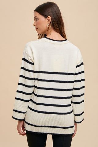 Woman wearing an ivory side slit striped round neck sweater with ribbed detail, showcasing a basic style design.