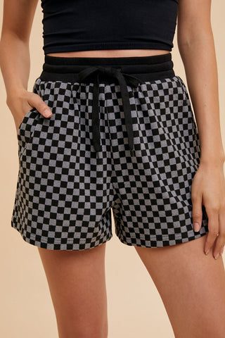 Black checkered drawstring shorts set with round neck top, featuring pockets and slight stretch, 93% polyester blend.