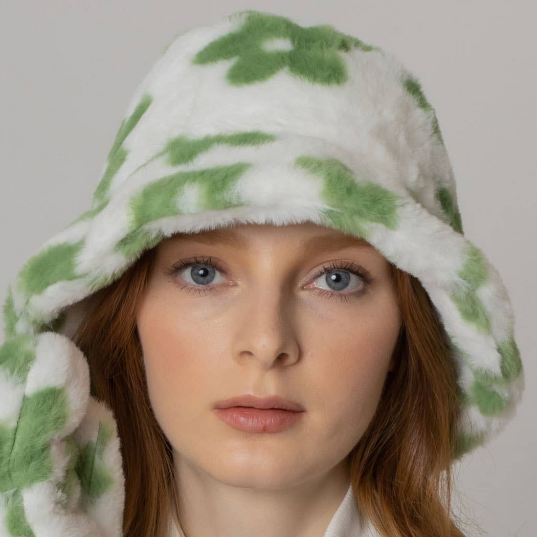 Woman wearing a floral printed faux fur bucket hat with green and white pattern, featuring a cozy flat top design and adjustable strings.