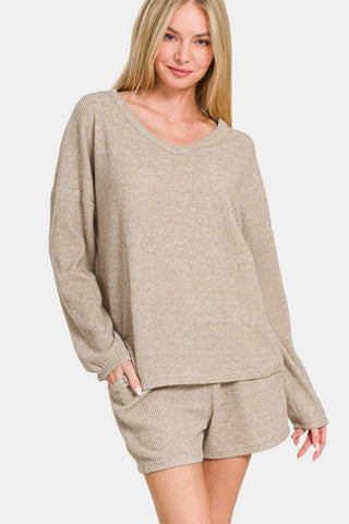 Woman wearing Zenana V-Neck Long Sleeve Ribbed Top and Shorts Set in beige, showcasing casual chic style with ribbed texture.