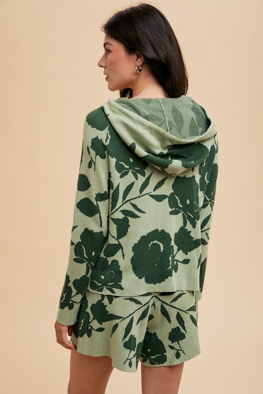 Woman wearing green flower pattern drawstring hooded sweater top and shorts set, slightly stretchy with ribbed details.