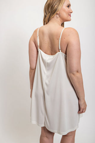 Woman wearing white V-neck slip dress with adjustable straps, back view