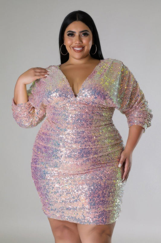 Blush pink sequin dress with long ruched sleeves, V-neck, and back zipper. Curvy fit with shoulder pads for structure. 1XL to 3XL sizes.