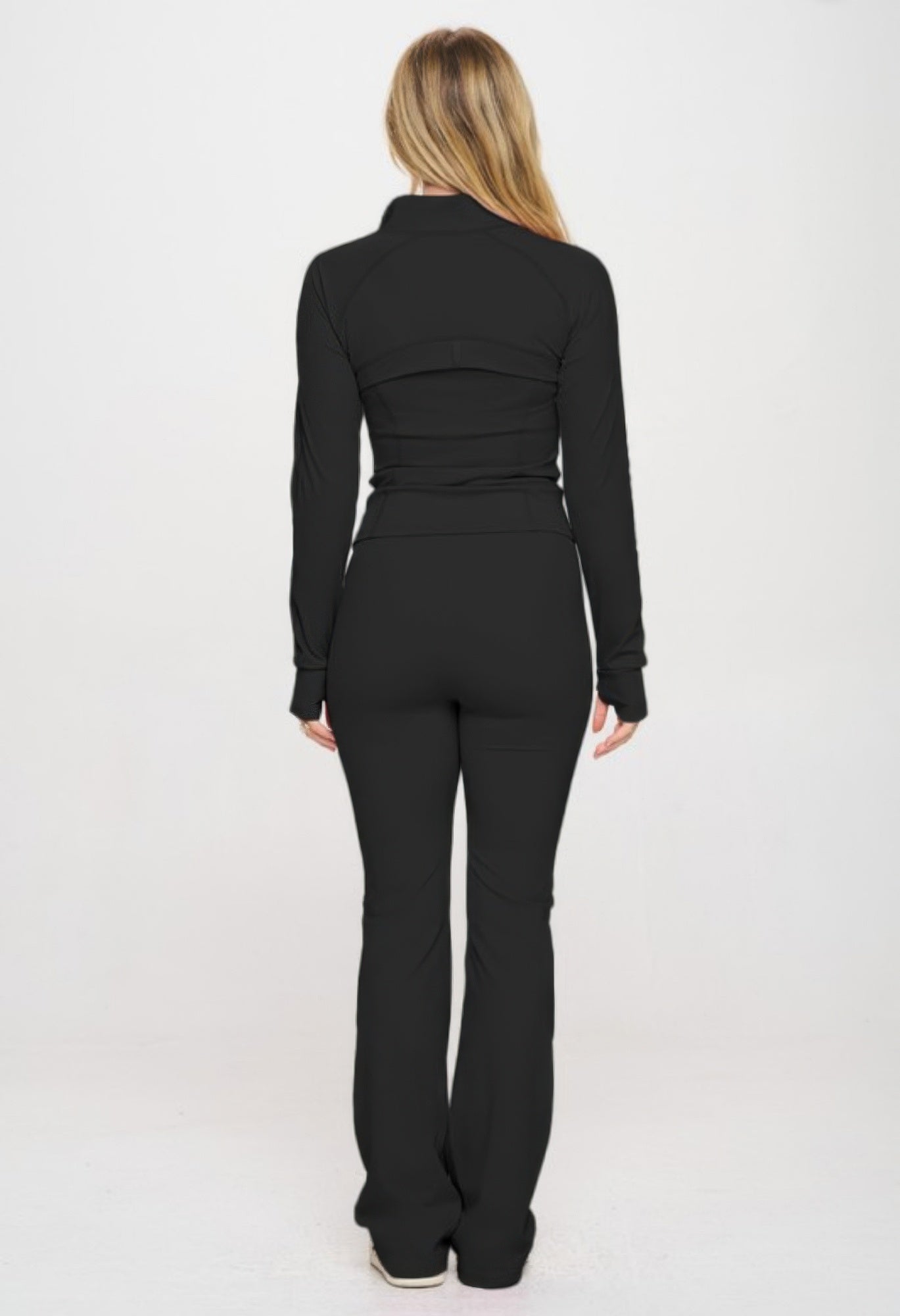 Back view of premium yoga jumpsuit set with fitted jacket, thumbhole sleeves, and flare-bottom, in black.