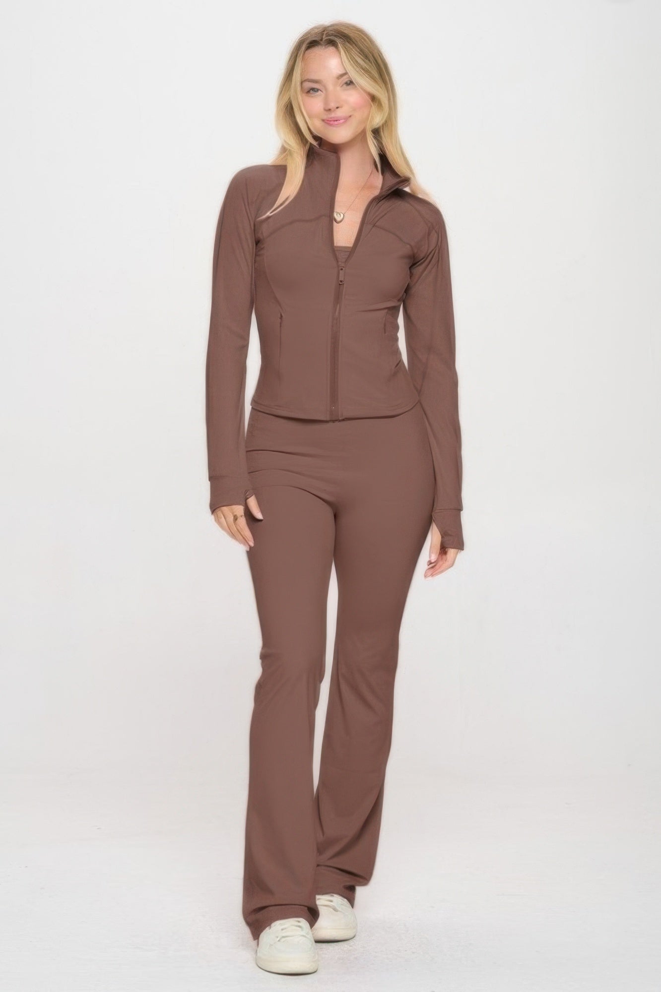 Model wearing premium yoga jacket and jumpsuit set in brown, showcasing thumbhole sleeves, flare-bottom pants, and fitted design.