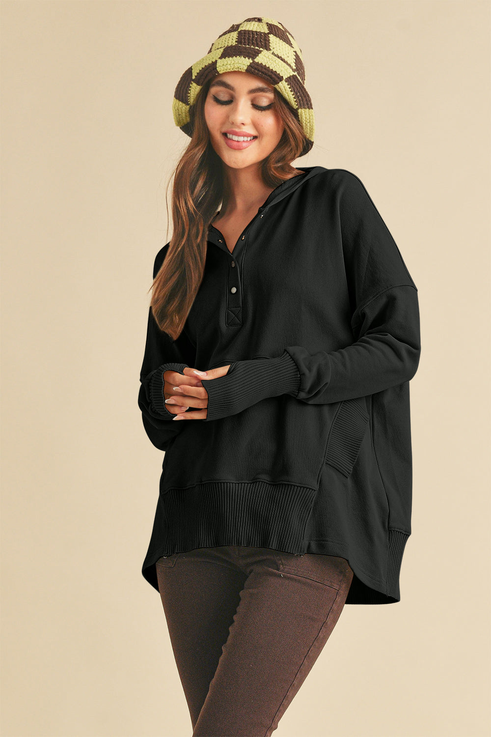 Black half snap dropped shoulder hoodie with ribbed cuffs, exposed seam, high-low hem, worn by model with checkered hat.